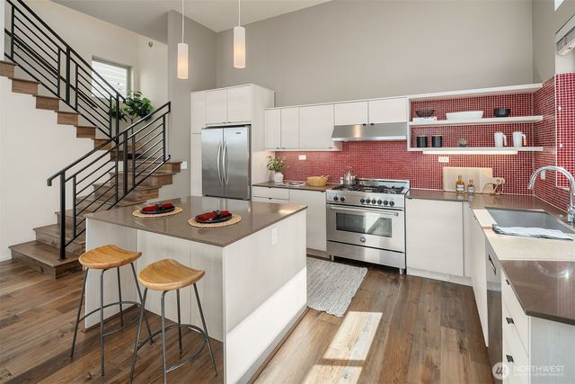 a kitchen with stainless steel appliances a stove a chimney a sink and cabinets