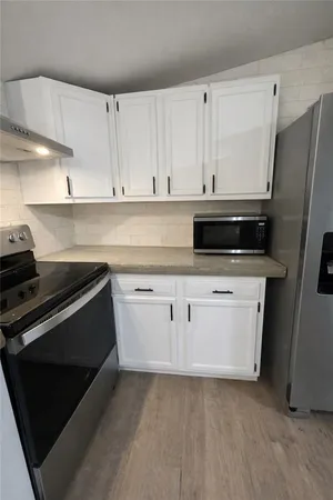 a kitchen with white cabinets and stainless steel appliances