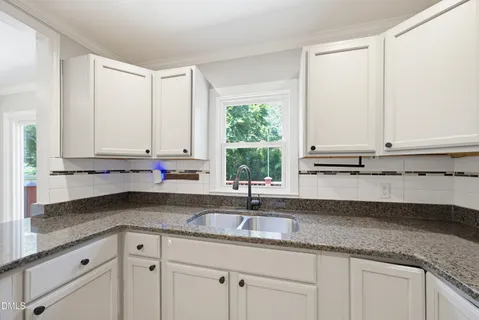 a kitchen with granite countertop white cabinets and a sink