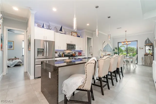 a large white living room with stainless steel appliances kitchen island granite countertop a sink and a flat screen tv