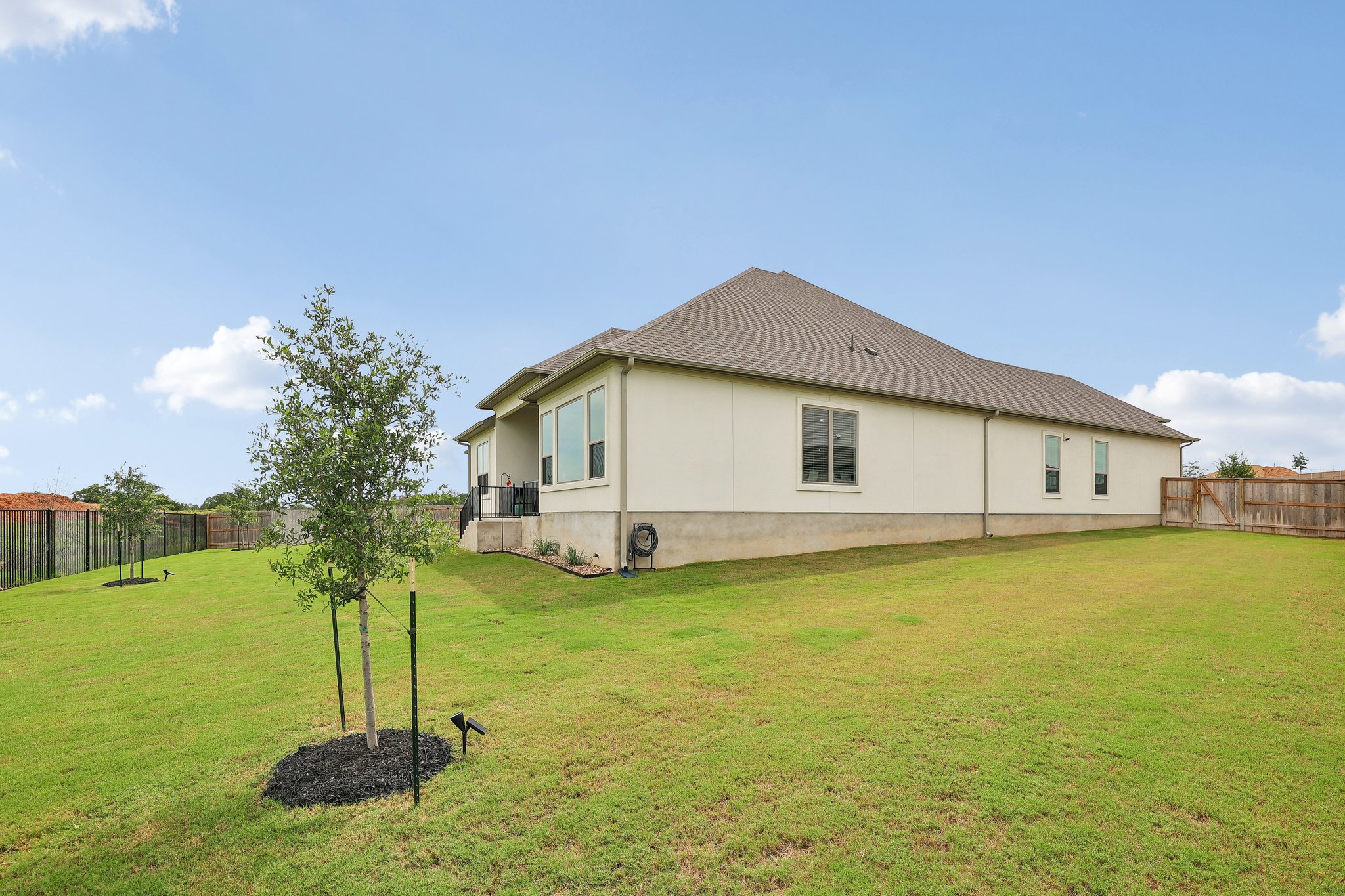 130 Firethorn Loop Bastrop, TX 78602 - Photo 32 of 38 Expansive rear yard featuring a manicured lawn, established trees, and perimeter fencing