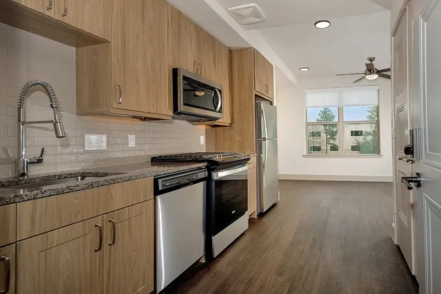 a kitchen with stainless steel appliances granite countertop a stove a sink and a microwave