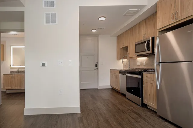 a kitchen with a refrigerator a stove top oven and wooden floor