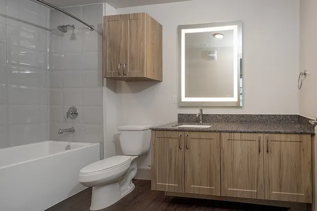 a bathroom with a granite countertop bathtub sink vanity and toilet