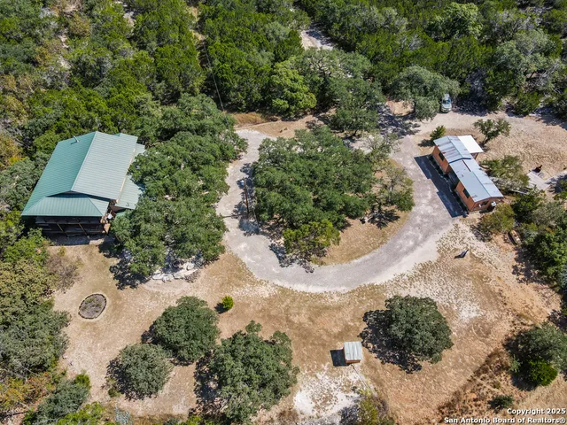 an aerial view of a house with a yard and trees all around