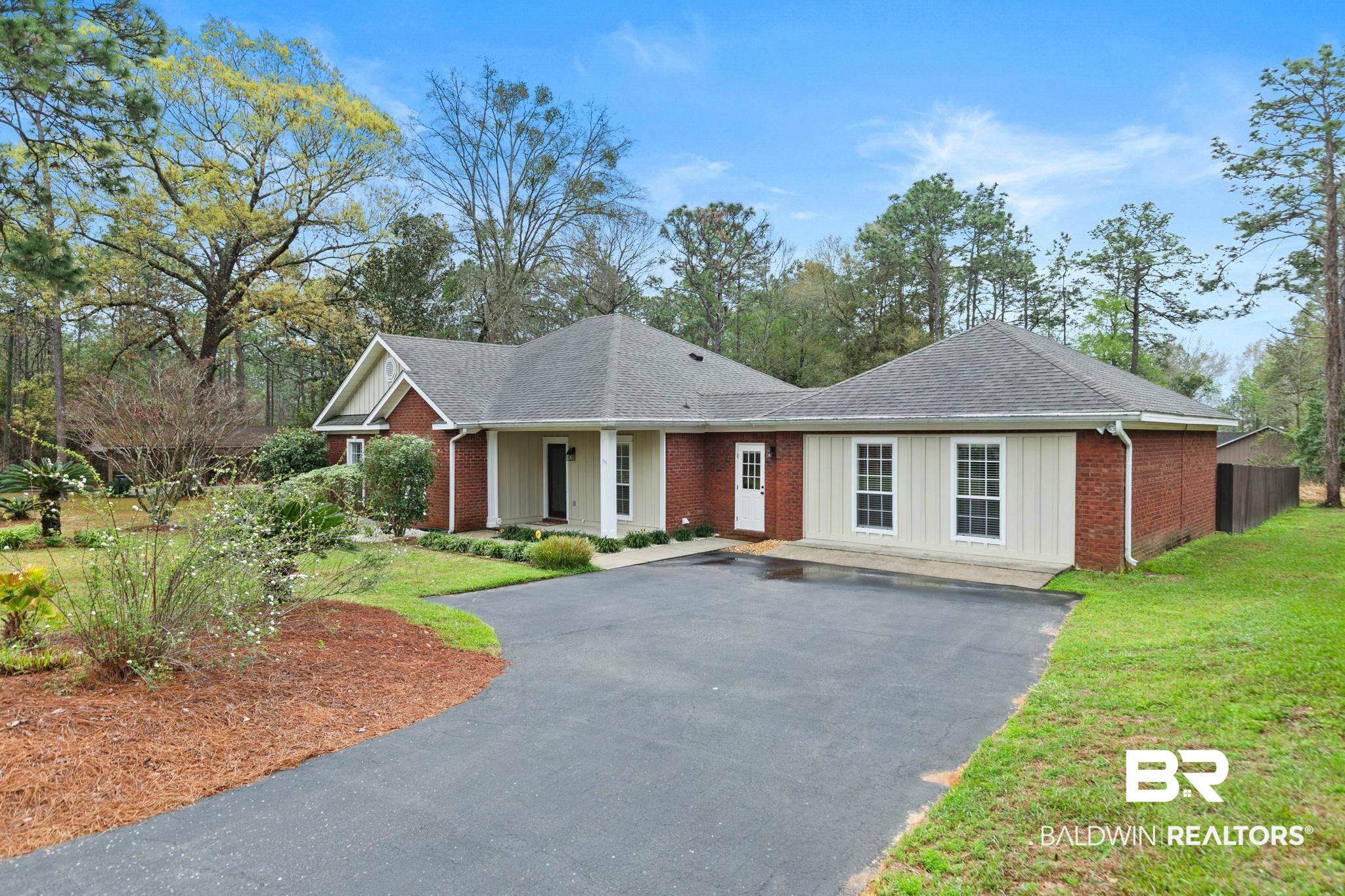 Ranch-style house featuring asphalt driveway, a shingled roof, board and batten siding, and brick siding