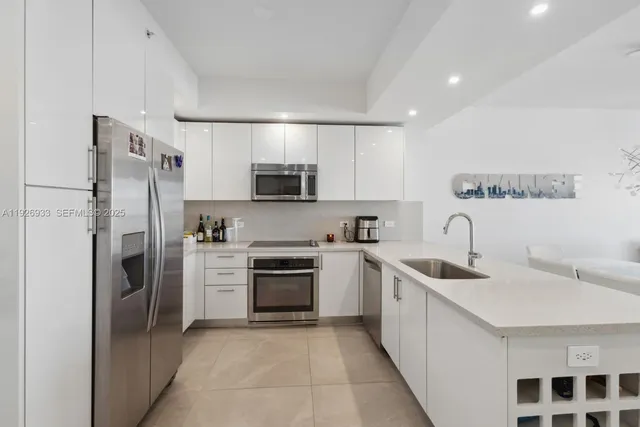 a kitchen with a sink a refrigerator and a stove top oven with wooden floor