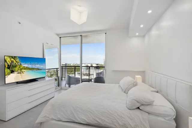a bedroom with a large bed and a flat tv screen on dresser