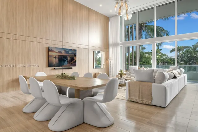 a living room with furniture a flat screen tv and floor to ceiling window