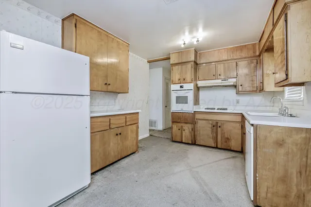 a kitchen with a sink a refrigerator and cabinets