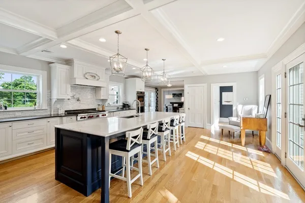 a large kitchen with lots of counter top space a sink appliances and living room view