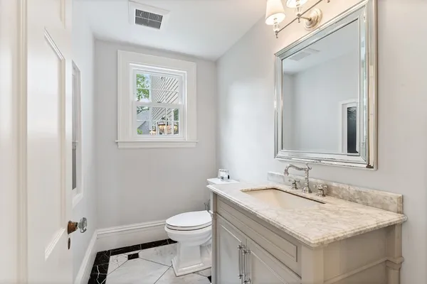 a bathroom with a granite countertop sink toilet and mirror