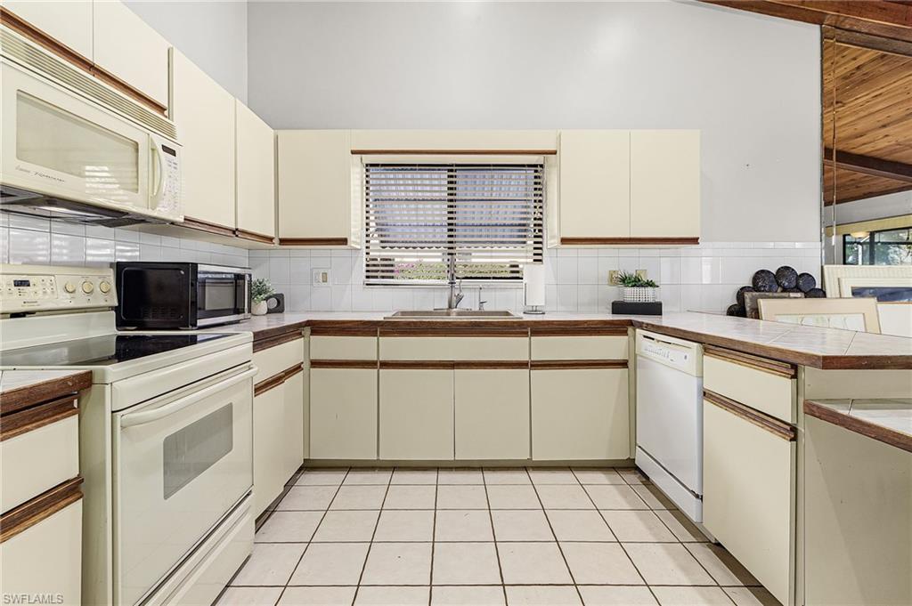 403 Southwest 34th Street Cape Coral, FL 33914 - Photo 17 of 32 Kitchen featuring white appliances, cream cabinets, tasteful backsplash, and a peninsula