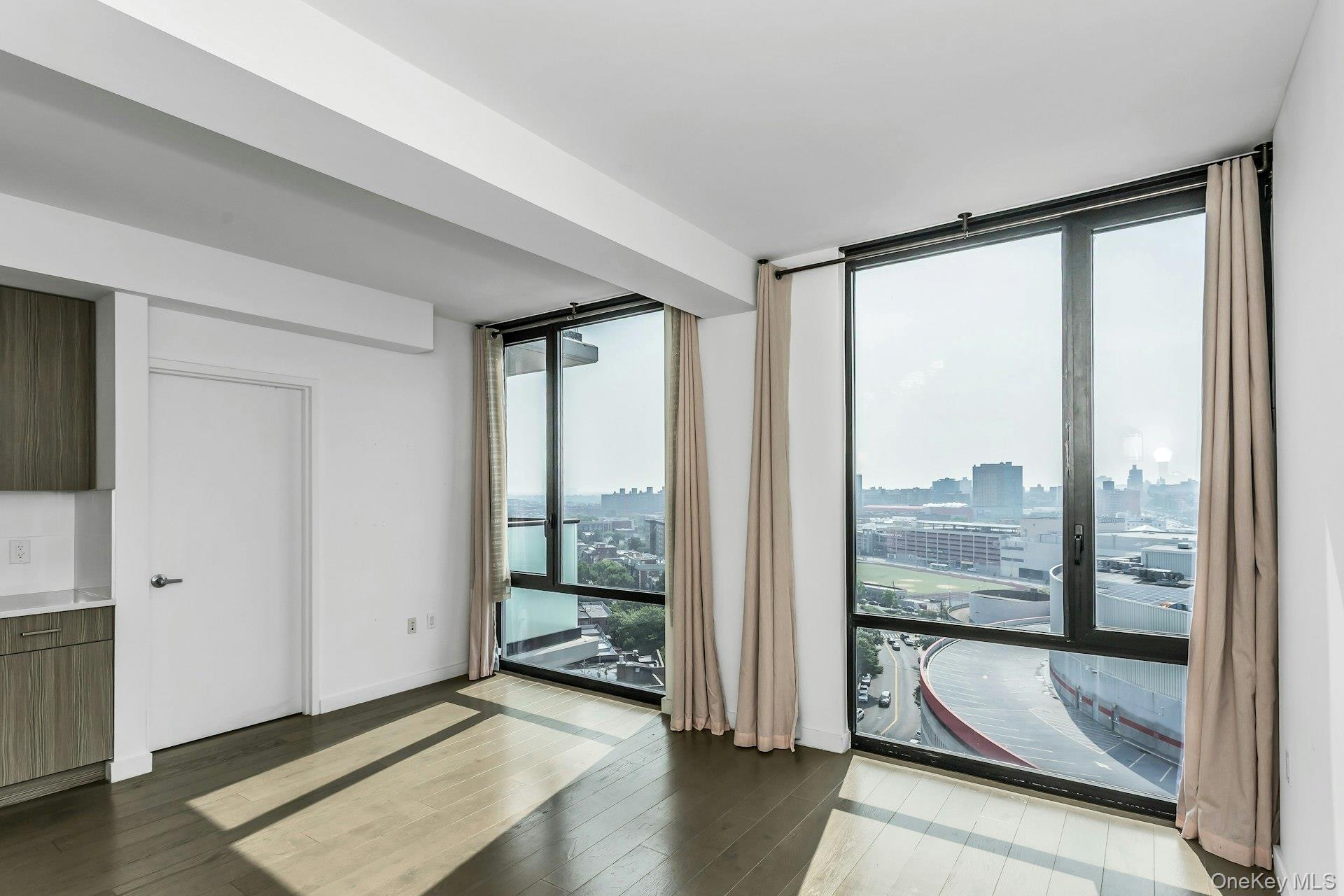 88-08 Justice Avenue, Unit 15N Queens, NY 11373 - Photo 4 of 20 a view of an empty room with wooden floor and a window