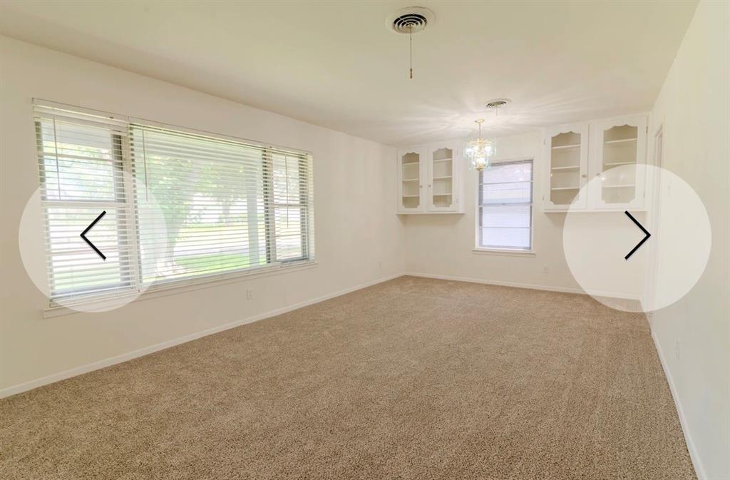 8017 Woodhue Road Dallas, TX 75228 - Photo 3 of 20 Carpeted room with multiple windows, a decorative ceiling light fixture, and built-in cabinetry with glass doors