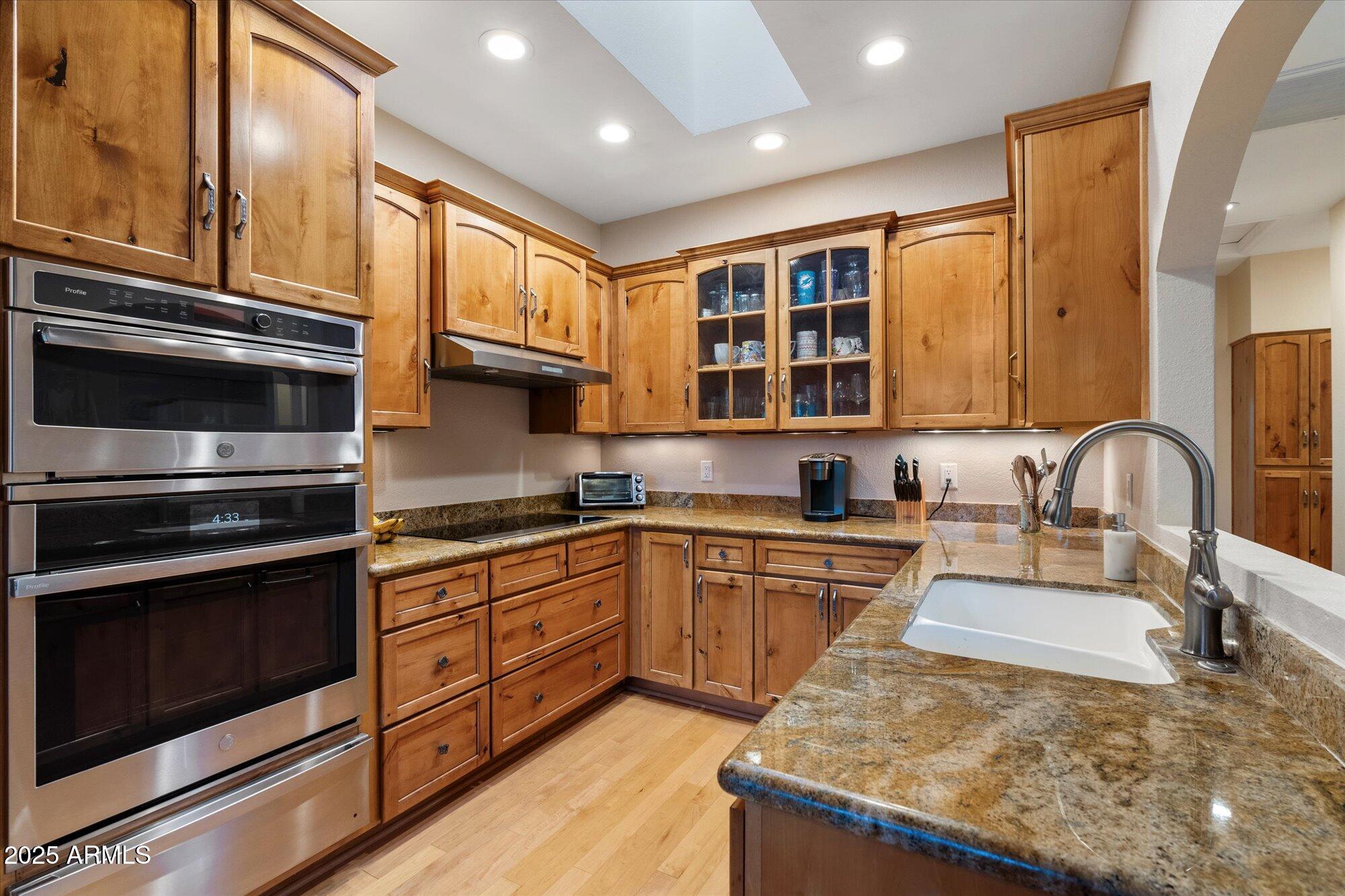 7272 East Gainey Ranch Road, Unit 104 Scottsdale, AZ 85258 - Photo 13 of 45 a kitchen with stainless steel appliances granite countertop a stove a sink and a microwave