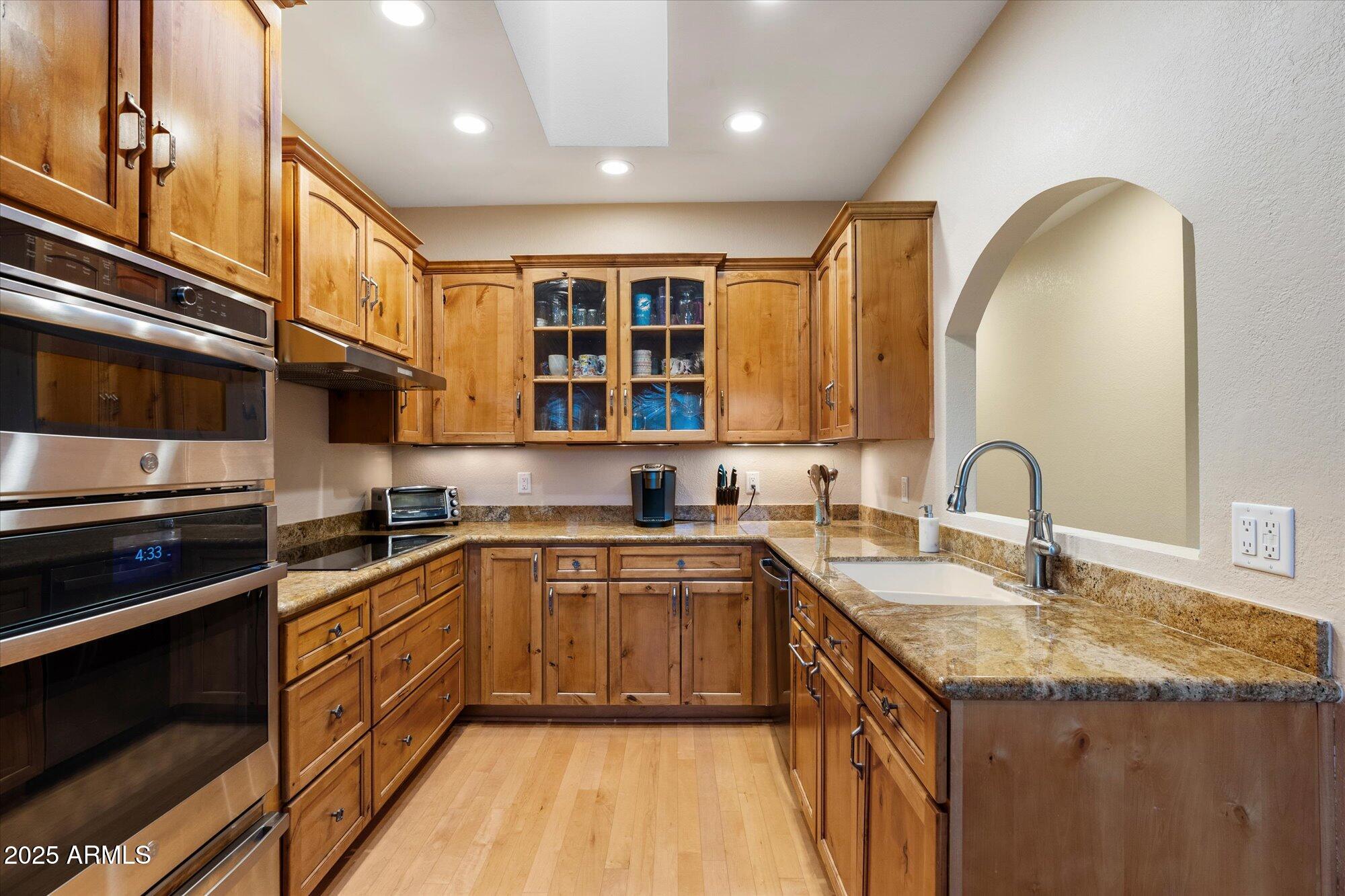 7272 East Gainey Ranch Road, Unit 104 Scottsdale, AZ 85258 - Photo 14 of 45 a kitchen with a sink and a stove top oven with wooden floor