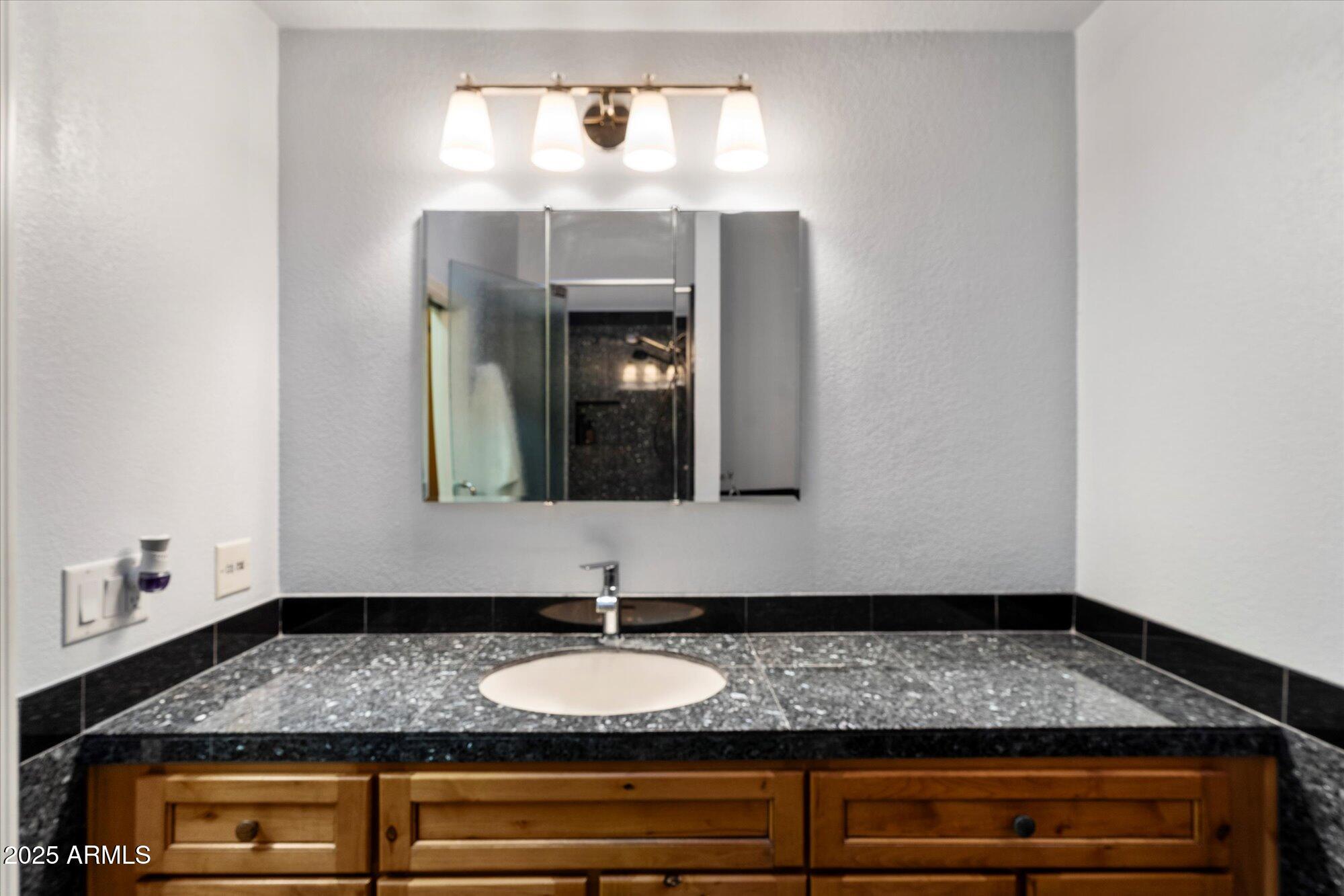7272 East Gainey Ranch Road, Unit 104 Scottsdale, AZ 85258 - Photo 25 of 45 a bathroom with a sink and a mirror