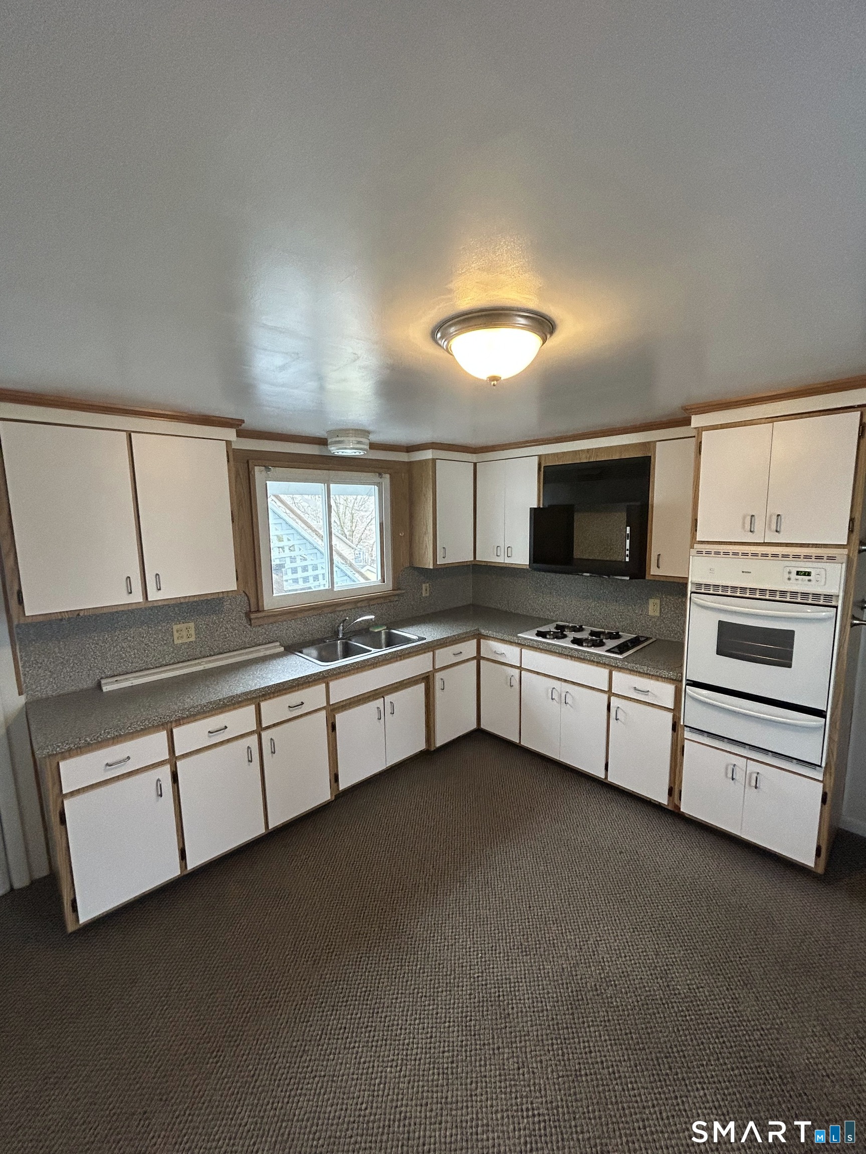 73 Peck Street, Unit 2 Norwich, CT 06360 - Photo 6 of 21 a large white kitchen with granite countertop a stove a sink and a dishwasher with white cabinets