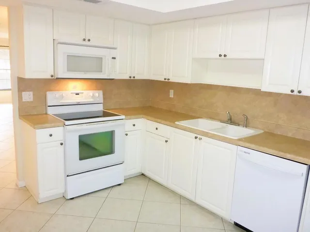 a kitchen with granite countertop white cabinets and white appliances