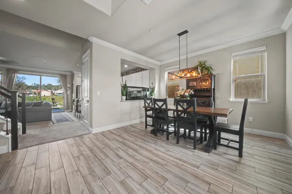 a kitchen with kitchen island granite countertop a stove top oven a sink dishwasher a dining table and chairs with wooden floor