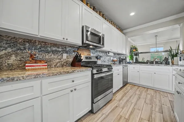 a kitchen with stainless steel appliances granite countertop a stove a sink and a microwave