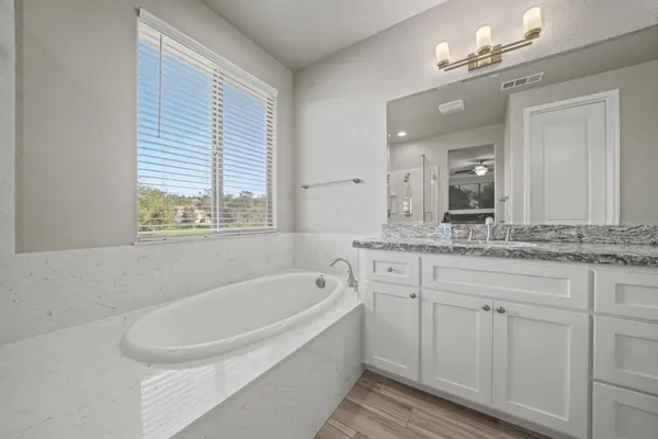 a bathroom with a granite countertop double vanity sink mirror and shower