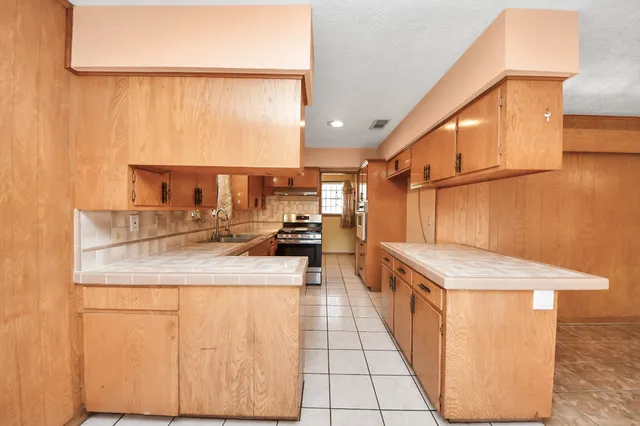 a kitchen with kitchen island a sink a counter top space and cabinets