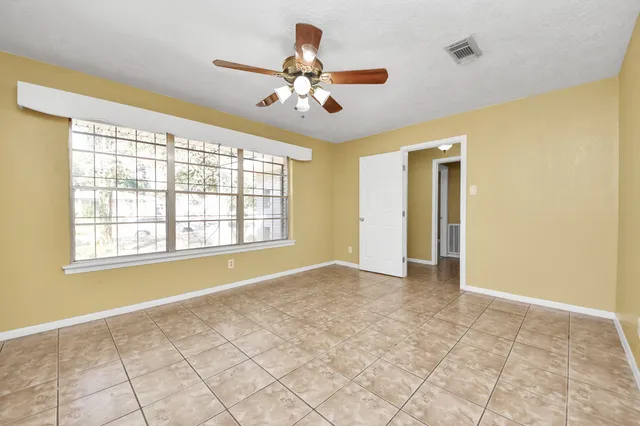 a view of an empty room with chandelier fan and fire place