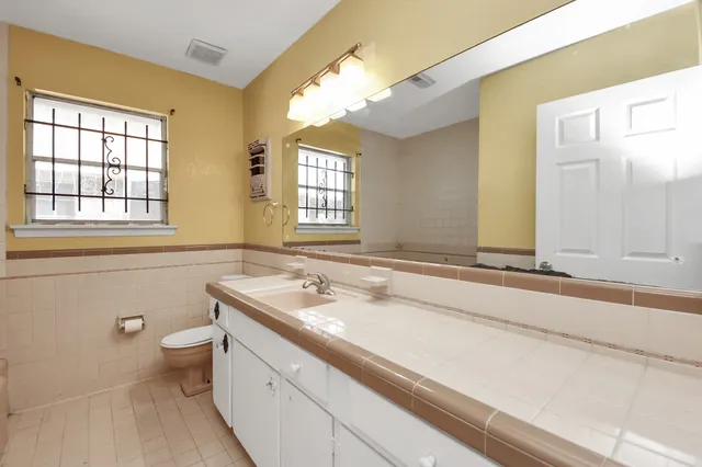 a bathroom with a sink a toilet a mirror and a window