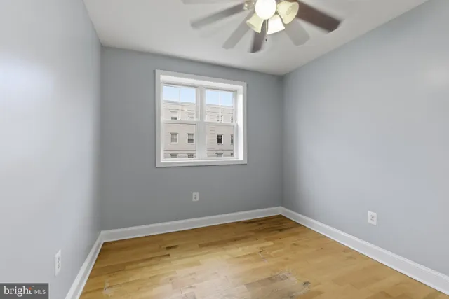 an empty room with a chandelier fan and windows