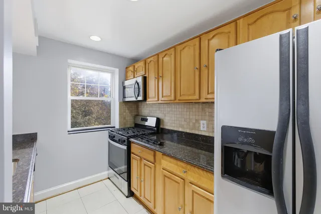 a kitchen with granite countertop cabinets stainless steel appliances and a window