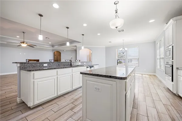 a kitchen with kitchen island granite countertop a sink cabinets and wooden floor