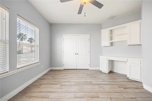 a view of empty room with wooden floor and fan