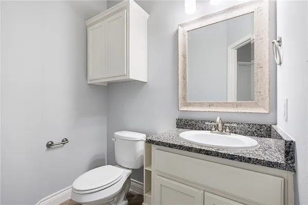 a bathroom with a granite countertop toilet sink and mirror