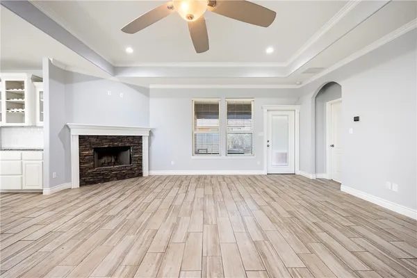 a view of an empty room with wooden floor fireplace and a window