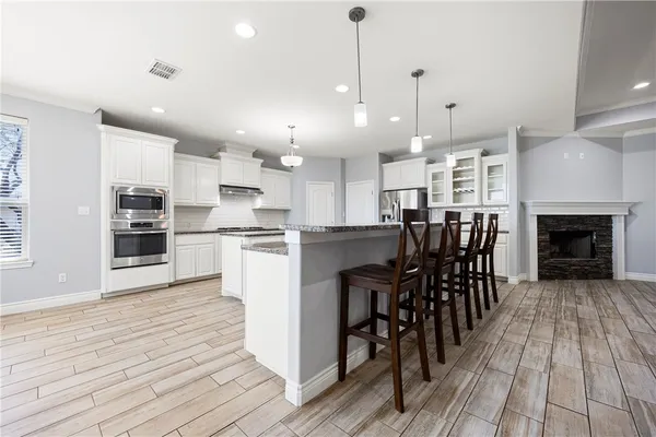 an open kitchen with wooden floor and stainless steel appliances