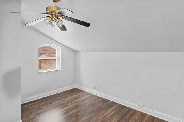 an empty room with wooden floor chandelier fan and windows