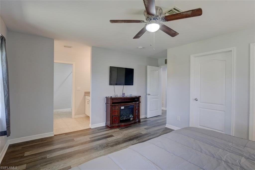 2812 4th Street Southwest Lehigh Acres, FL 33976 - Photo 19 of 34 a view of an empty room with a fireplace a ceiling fan and wooden floor