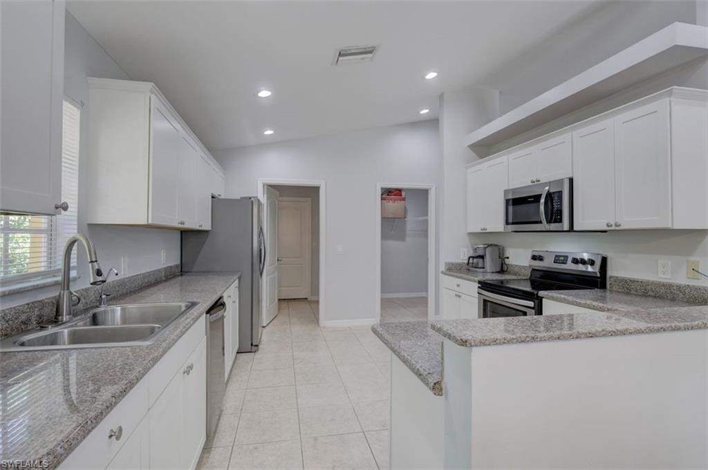 2812 4th Street Southwest Lehigh Acres, FL 33976 - Photo 10 of 34 a kitchen with stainless steel appliances granite countertop a sink stove microwave and refrigerator