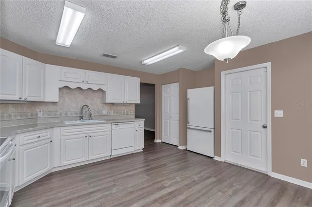 a kitchen with a refrigerator and white cabinets