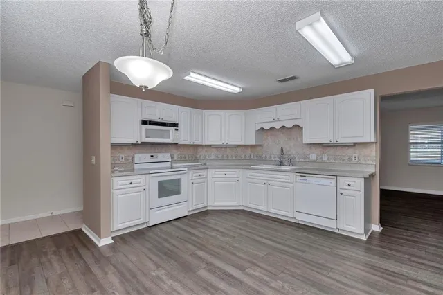a kitchen with stainless steel appliances granite countertop a stove and white cabinets with wooden floor