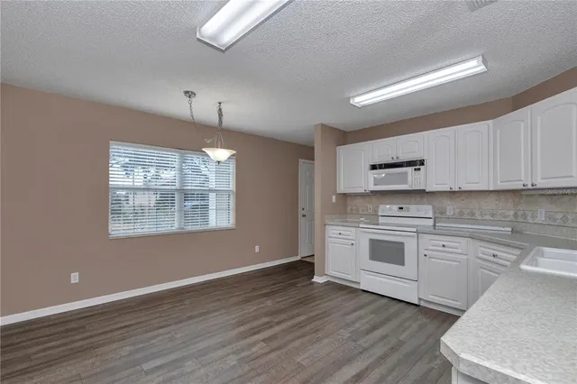 a kitchen with granite countertop white cabinets and white appliances