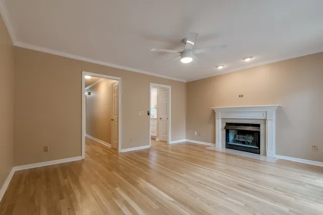 an empty room with wooden floor fireplace and windows