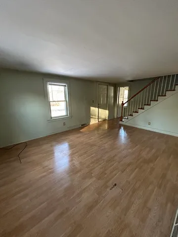 a view of an empty room with window and wooden floor