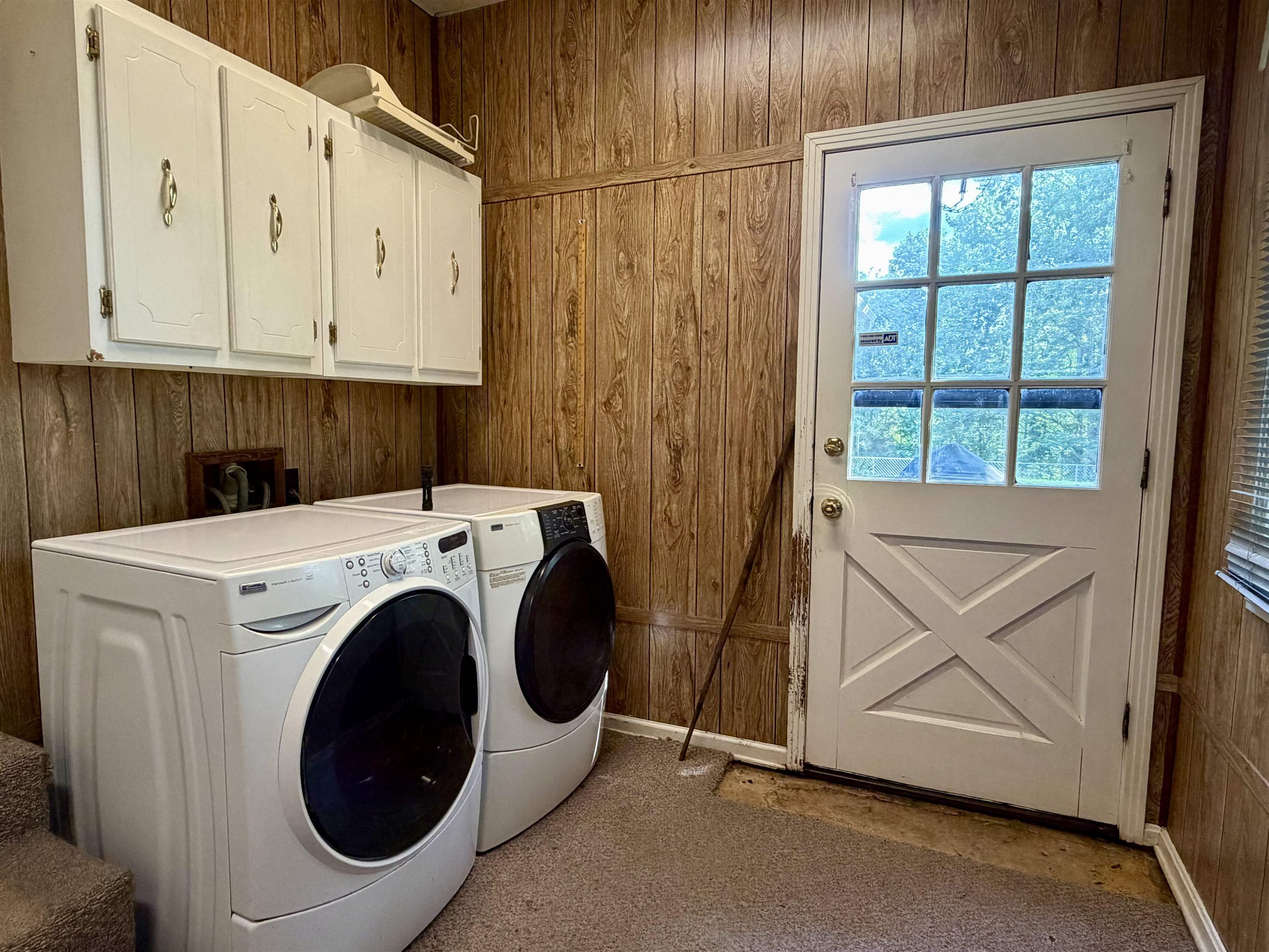 373 Clarence Barham Road Bethel Springs, TN 38315 - Photo 19 of 28 Laundry area featuring wood-finish wall paneling and overhead white cabinetry