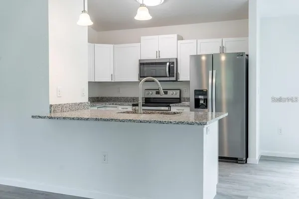 a kitchen with stainless steel appliances granite countertop a refrigerator a stove a sink and a granite counter tops