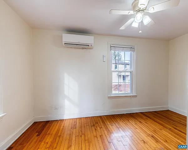 an empty room with wooden floor chandelier fan and windows