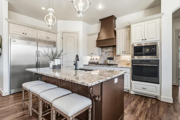a kitchen with kitchen island granite countertop a sink cabinets and stainless steel appliances