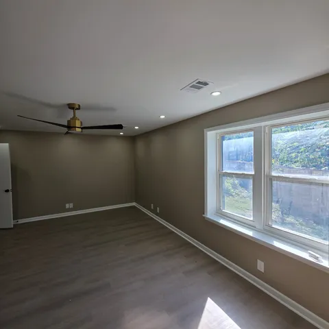 an empty room with wooden floor and windows